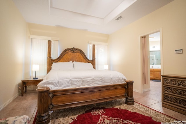 bedroom featuring light tile patterned floors, visible vents, baseboards, and a tray ceiling