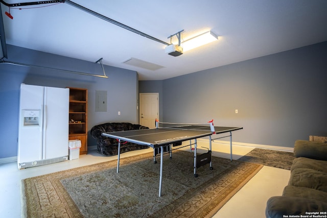 game room featuring electric panel, a garage, baseboards, and concrete floors