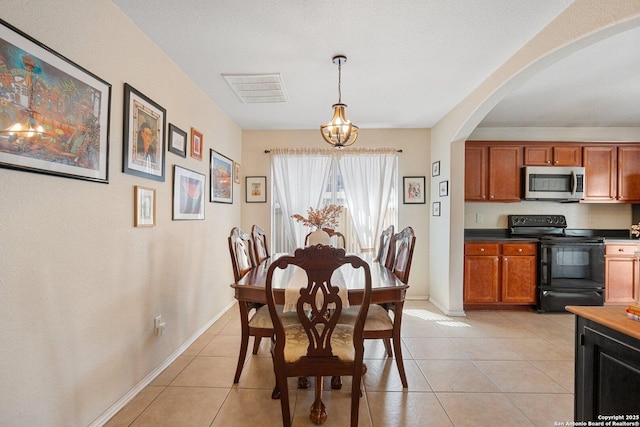 dining space with light tile patterned flooring, a notable chandelier, arched walkways, and visible vents