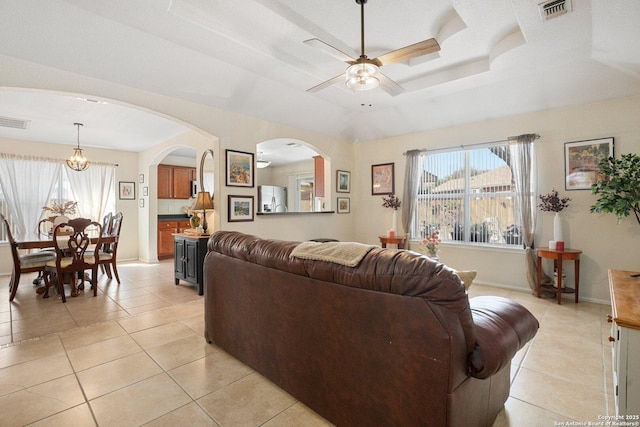 living room featuring a tray ceiling, a healthy amount of sunlight, visible vents, and ceiling fan