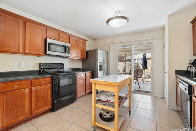 kitchen featuring brown cabinets, open shelves, dark countertops, appliances with stainless steel finishes, and light tile patterned flooring