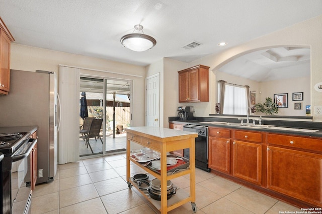 kitchen with visible vents, black appliances, a sink, dark countertops, and arched walkways