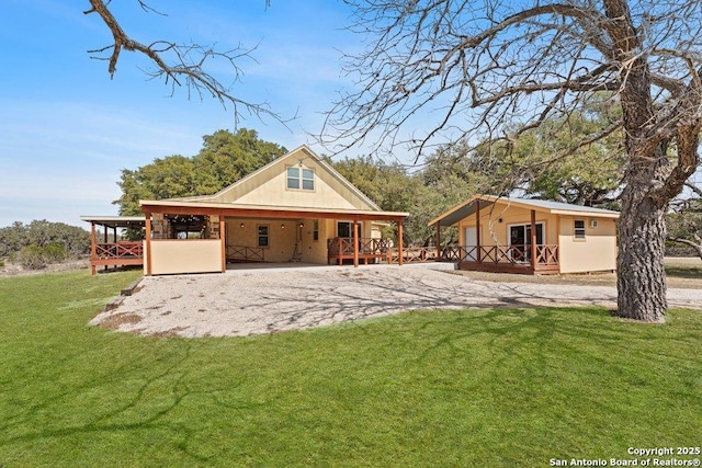 rear view of house with a wooden deck, a lawn, and driveway