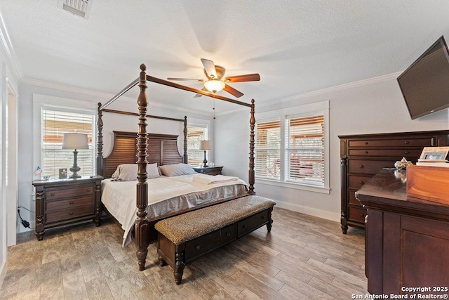 bedroom featuring visible vents, a textured ceiling, ornamental molding, and light wood finished floors