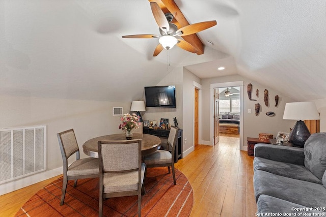 dining room featuring visible vents, light wood finished floors, baseboards, and vaulted ceiling