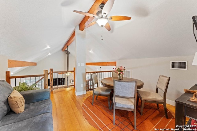 dining room featuring visible vents, baseboards, hardwood / wood-style floors, and vaulted ceiling with beams