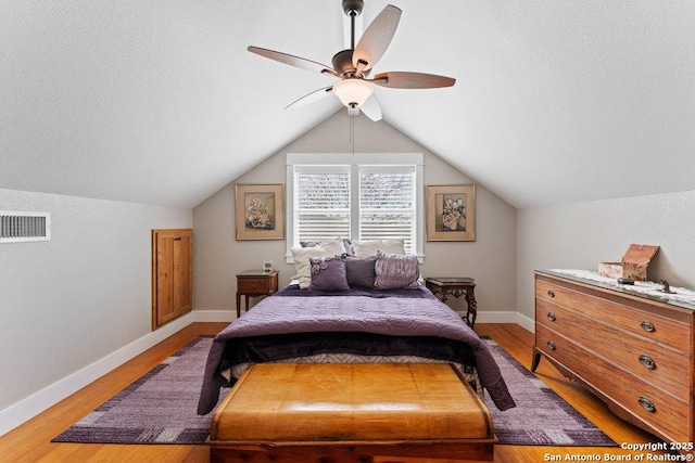 bedroom featuring baseboards, visible vents, lofted ceiling, light wood-style flooring, and ceiling fan