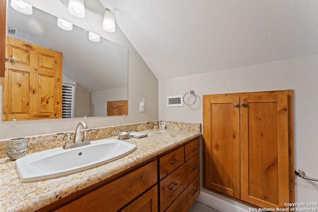 bathroom with visible vents, lofted ceiling, and vanity