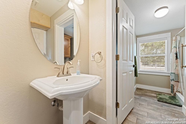 full bath with visible vents, baseboards, wood finished floors, and a textured wall