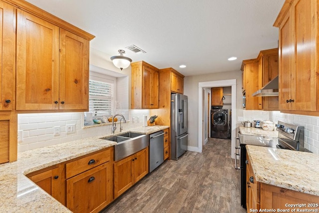 kitchen with visible vents, under cabinet range hood, a sink, washer / clothes dryer, and appliances with stainless steel finishes