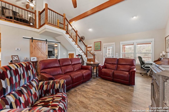 living room with stairs, a barn door, wood finished floors, high vaulted ceiling, and a ceiling fan