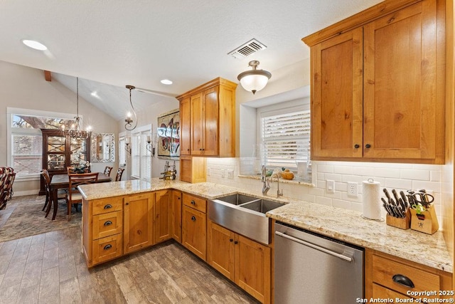 kitchen featuring wood finished floors, a peninsula, lofted ceiling, a sink, and stainless steel dishwasher