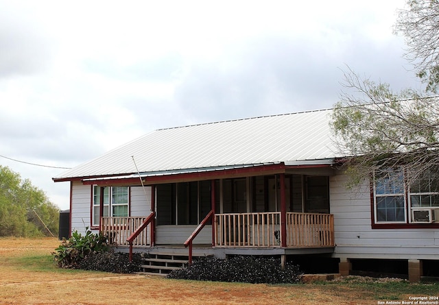 view of front of home featuring covered porch, metal roof, and a front yard