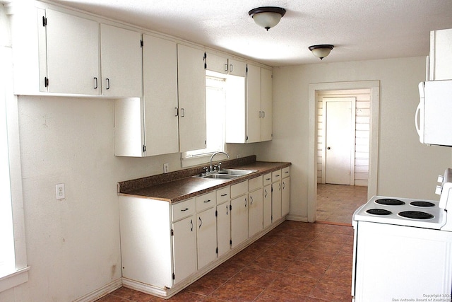 kitchen featuring white appliances, baseboards, a sink, a textured ceiling, and dark countertops