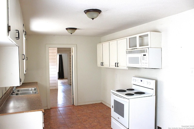 kitchen featuring a sink, white cabinetry, white appliances, glass insert cabinets, and baseboards