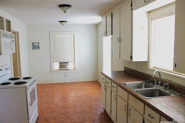 kitchen with dark countertops, a sink, baseboards, white appliances, and dark tile patterned flooring