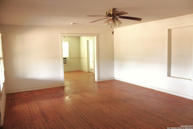 spare room with baseboards, wood finished floors, and a ceiling fan