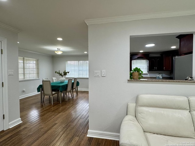 living area with dark wood finished floors, baseboards, a wealth of natural light, and ornamental molding