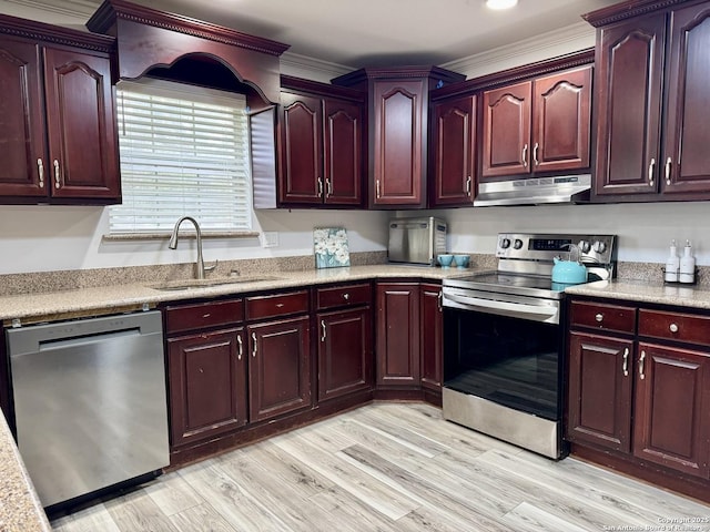 kitchen with light wood-style flooring, under cabinet range hood, a sink, stainless steel appliances, and reddish brown cabinets