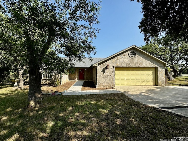 view of front of property with stone siding, an attached garage, concrete driveway, and a front yard