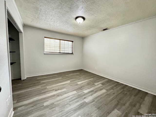 unfurnished room featuring visible vents, baseboards, a textured ceiling, and dark wood-style flooring