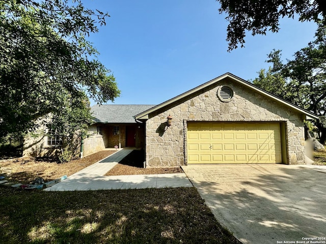 ranch-style house with stone siding, an attached garage, and driveway