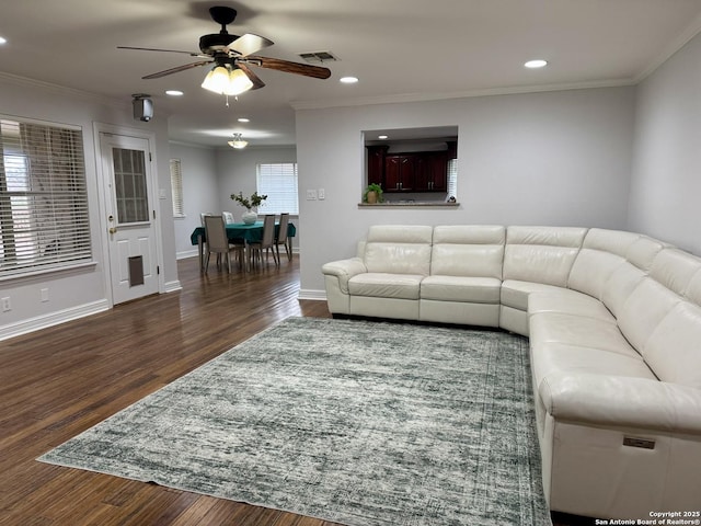 living area with baseboards, wood finished floors, visible vents, and ornamental molding