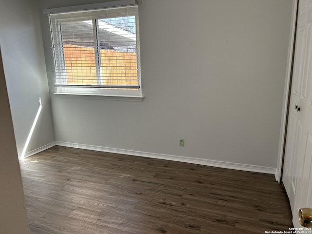 empty room with dark wood-type flooring and baseboards