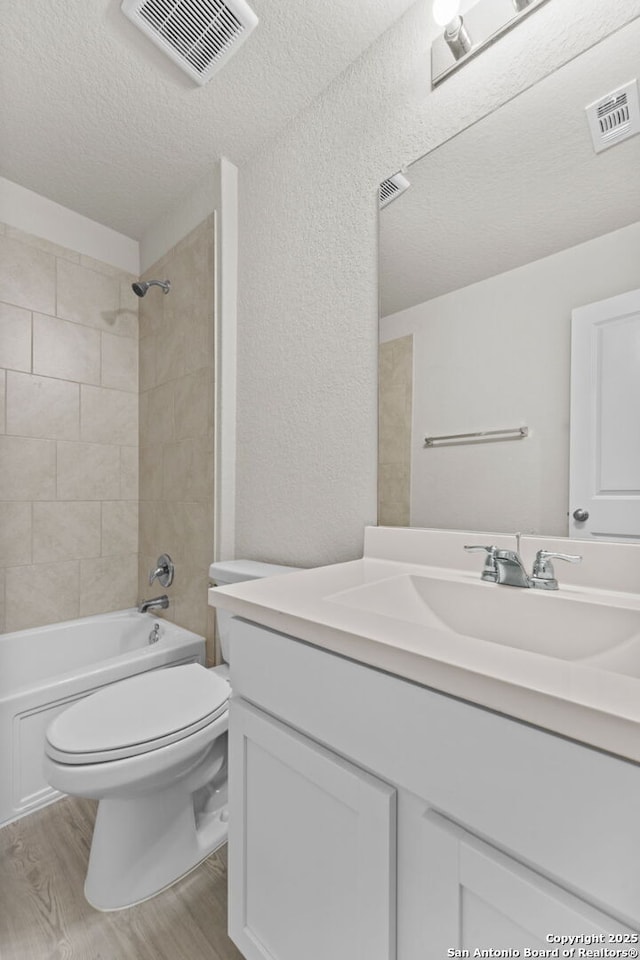 full bath featuring vanity, toilet, wood finished floors, and visible vents