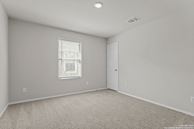 carpeted empty room with visible vents, a textured ceiling, and baseboards