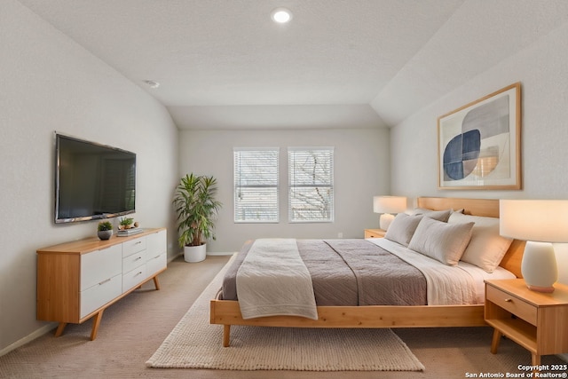 bedroom featuring lofted ceiling, baseboards, and light carpet