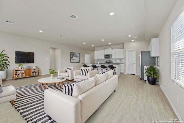 living room with light wood-style flooring, recessed lighting, visible vents, and baseboards