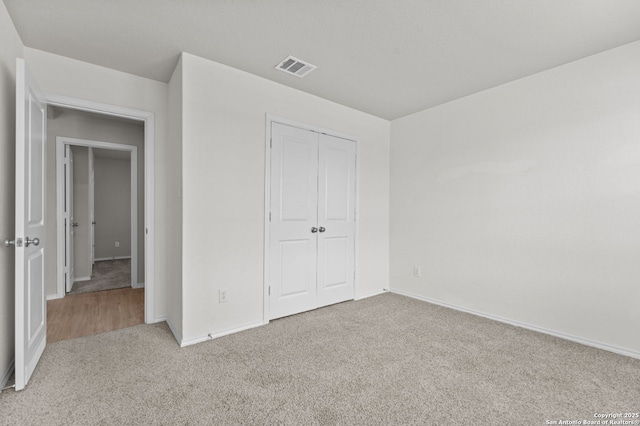 unfurnished bedroom with visible vents, baseboards, carpet, and a closet