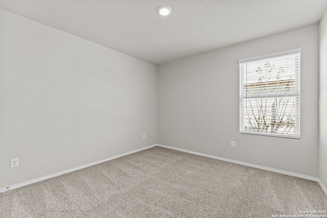 unfurnished room featuring light colored carpet, baseboards, and a textured ceiling