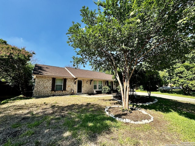 ranch-style house with stone siding and a front yard