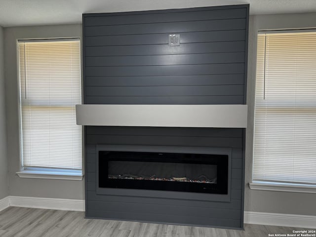 room details with baseboards, a large fireplace, a textured ceiling, and wood finished floors