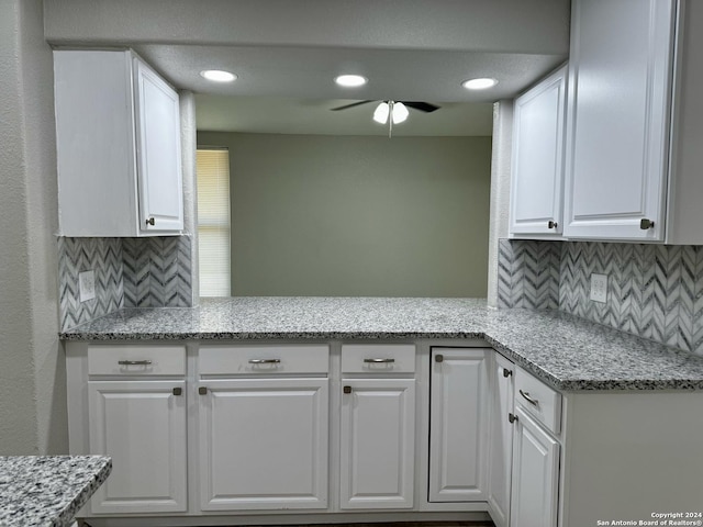 kitchen with decorative backsplash, light stone countertops, white cabinets, and a ceiling fan