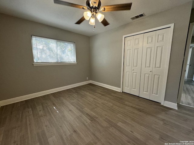 unfurnished bedroom with visible vents, dark wood-type flooring, baseboards, a closet, and a ceiling fan