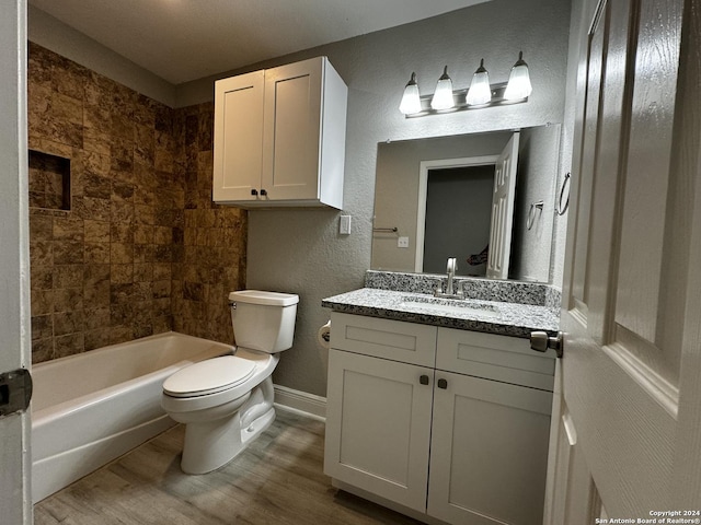 bathroom with baseboards, toilet, wood finished floors, a textured wall, and vanity