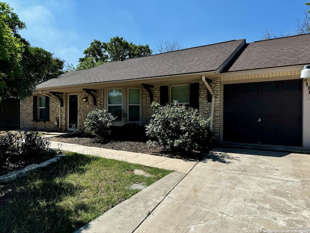 single story home featuring concrete driveway, a shingled roof, and a garage