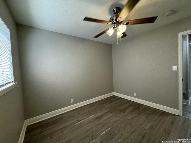 empty room featuring ceiling fan, dark wood-type flooring, and baseboards