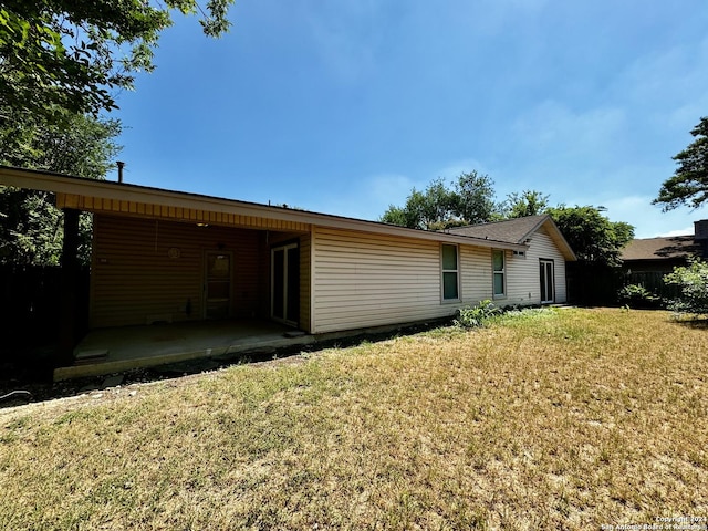 rear view of property featuring a patio and a yard