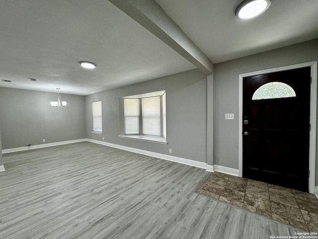 entrance foyer with wood finished floors, visible vents, baseboards, a textured ceiling, and a notable chandelier