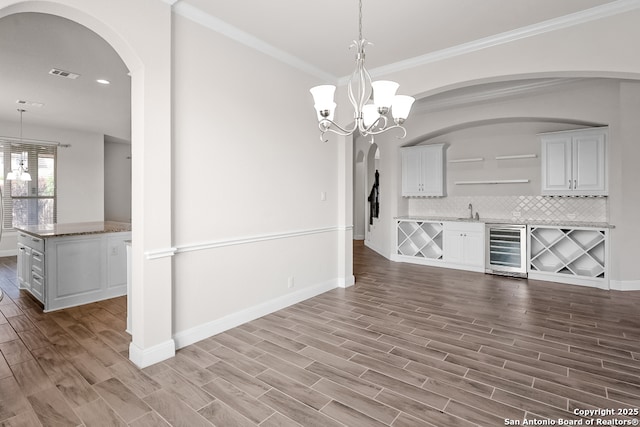 605 Albarella, Cibolo, TX 78108 - unfurnished dining area with wine cooler, wood finished floors, baseboards, arched walkways, and a sink
