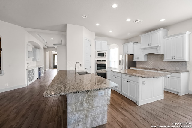 605 Albarella, Cibolo, TX 78108 - kitchen with arched walkways, a center island with sink, appliances with stainless steel finishes, a sink, and dark wood-type flooring