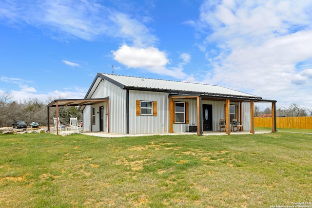 back of house with metal roof, a lawn, and fence