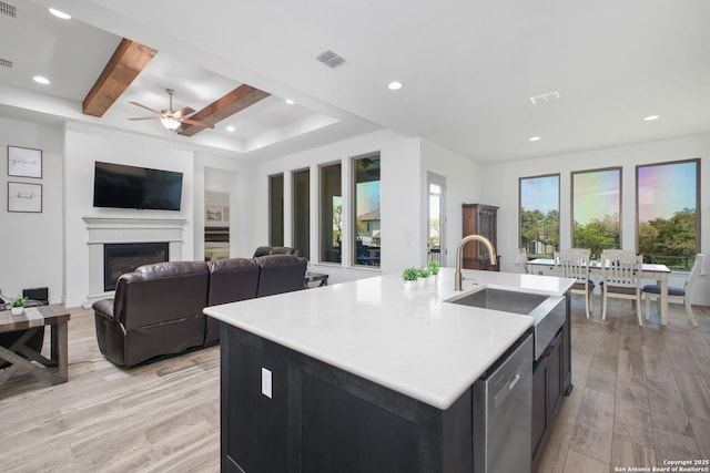 kitchen featuring stainless steel dishwasher, a fireplace, light wood-style flooring, visible vents, and a sink