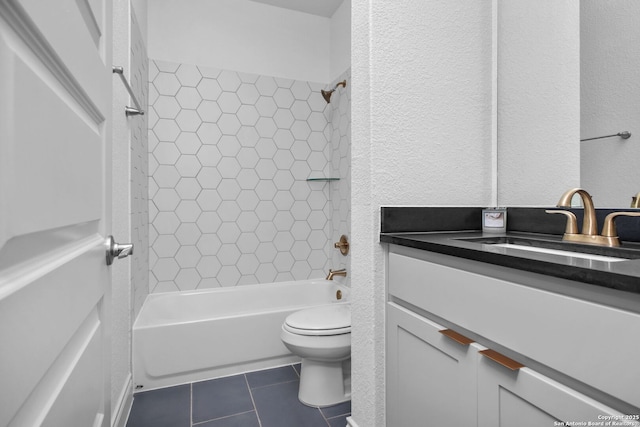 bathroom featuring toilet, a textured wall, vanity, tile patterned floors, and bathing tub / shower combination