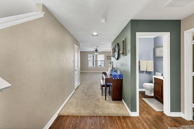 hallway with visible vents, baseboards, and dark wood-type flooring