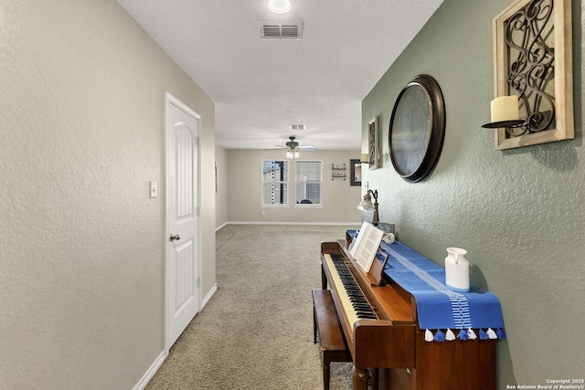 hall featuring carpet, visible vents, baseboards, a textured ceiling, and a textured wall